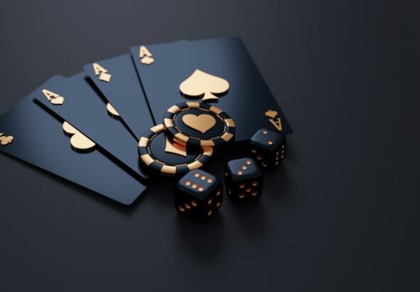 Black playing cards with gold aces, poker chips, and dice on dark surface